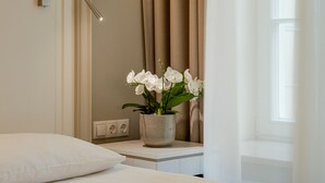 A hotel room with a bed, a bedside lamp, a vase with flowers, and a window with curtains. - Ratonda Centrum Hotels (Vilnius)