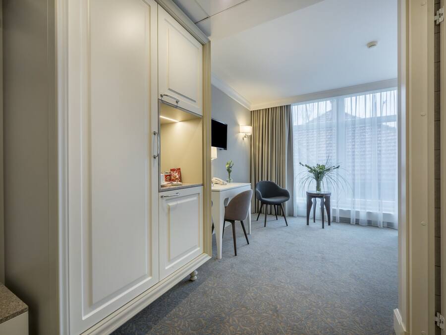 A hotel room with a desk, chair, and a television mounted on the wall.