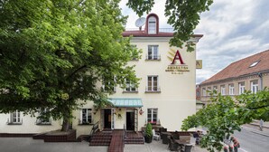 Un hôtel avec une enseigne indiquant «Amber Hotel», une antenne parabolique sur le toit et des tables et des chaises disposées à l’extérieur pour créer un espace de détente.