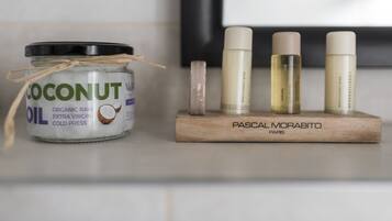 Un tarro de aceite de coco, un bloque de madera con productos para el cuidado de la piel y un pequeño cristal en una estantería.