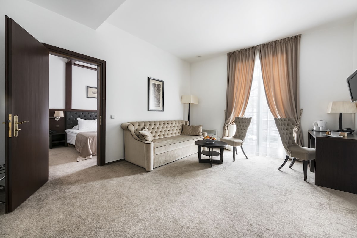 Une chambre d’hôtel avec un canapé, une petite table ronde, une chaise, un lit et un téléviseur.