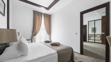 Une chambre d’hôtel moderne avec un grand lit, une fenêtre avec des rideaux, une porte donnant sur un balcon et un tableau encadré au mur.