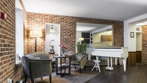 Un salon avec un piano, des murs en briques et un grand miroir.