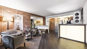 Un salon moderne avec un piano, un canapé, une table basse et un mur en briques.