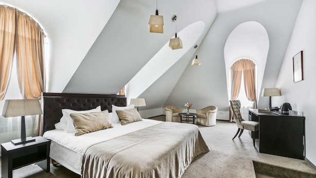 Une chambre à coucher moderne avec un grand lit, des tables de chevet, un bureau et une chaise.