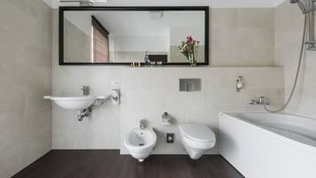 Ein modernes Badezimmer mit einer Bidet-Funktion, Toilette, Waschbecken und Badewanne.