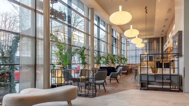 A spacious indoor area with large windows, modern furniture, and hanging lights. - Radisson Hotel Kaunas (Kaunas)