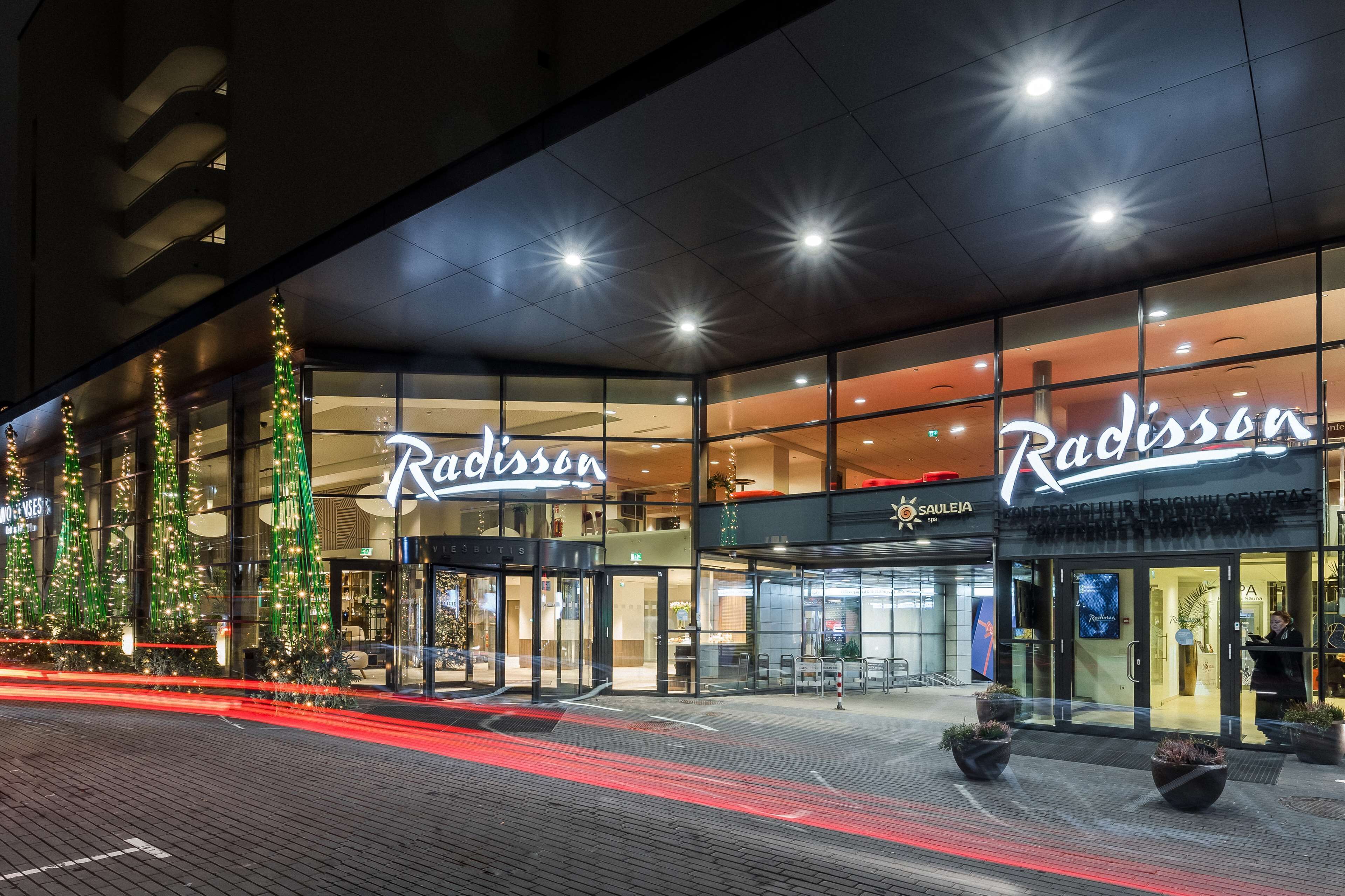 A Radisson hotel with a modern glass facade, illuminated signage, and a well-lit entrance area.