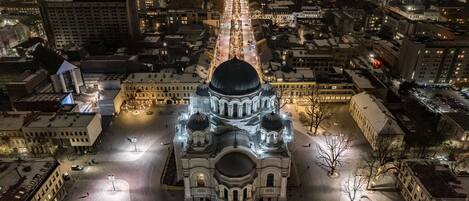 An aerial view of a historic building with a central dome and multiple smaller domes, surrounded by a cityscape at night.