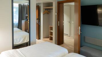 Een hotelkamer met een bed, een spiegel, een kledingkast, een televisie en een badkamer.