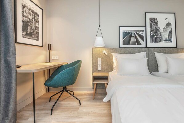 Relax in a serene space with a neatly made bed, comfortable chair, and functional desk.