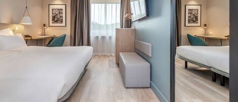 Una habitación de hotel moderna con dos camas, un escritorio, un banco y un espejo grande.