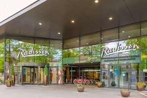 Enter through the revolving door, marked by potted plants, into the hotel.