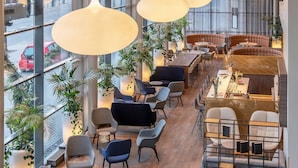 A modern interior with large windows, multiple seating areas, and hanging pendant lights. - Radisson Hotel Kaunas (Kaunas)