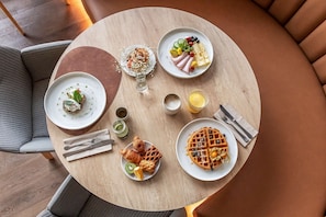 Enjoy a delicious breakfast spread at this inviting dining table, complete with waffles, croissants, fresh fruits, and cheese.