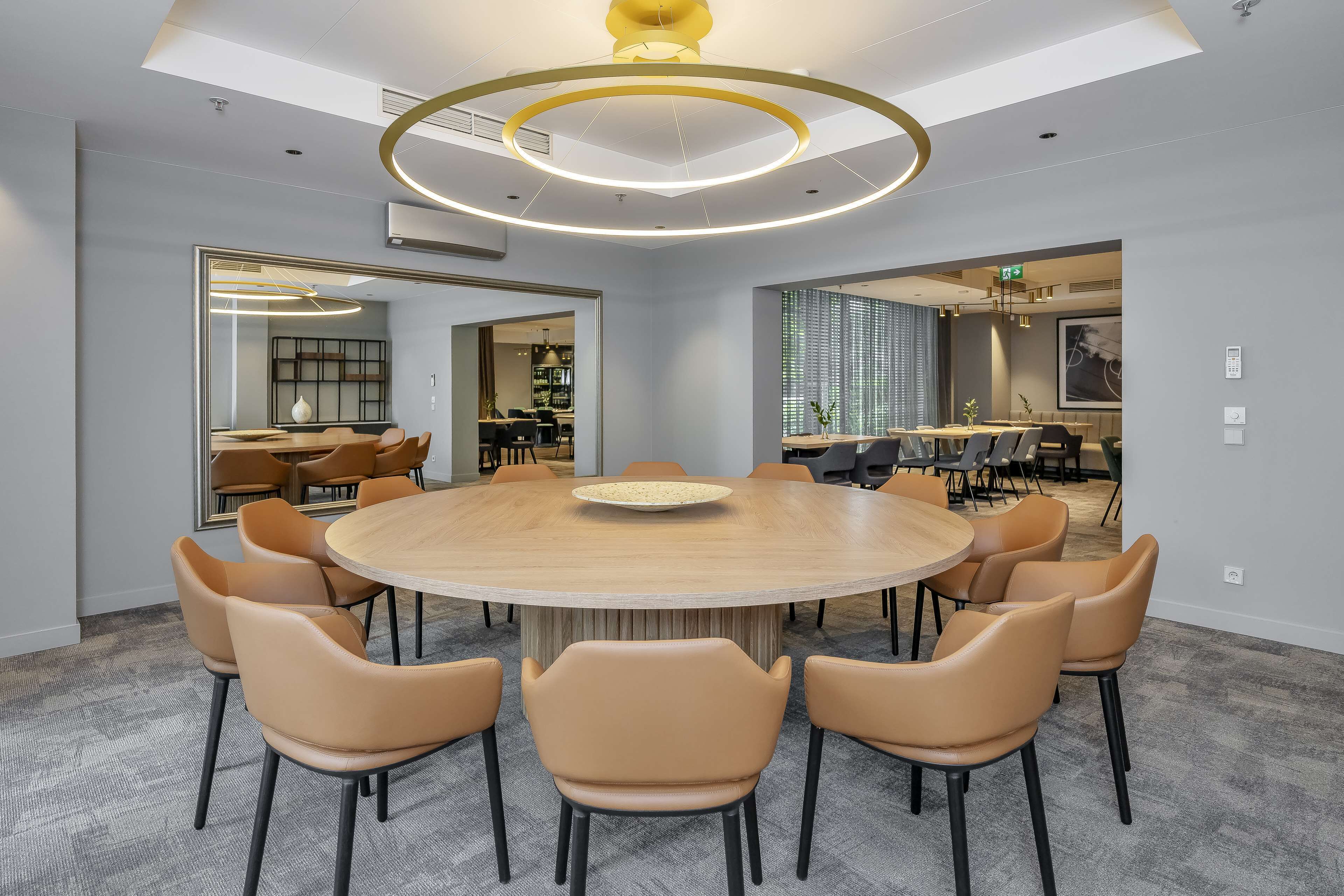 A conference room with a round table, beige chairs, and a modern ceiling design.