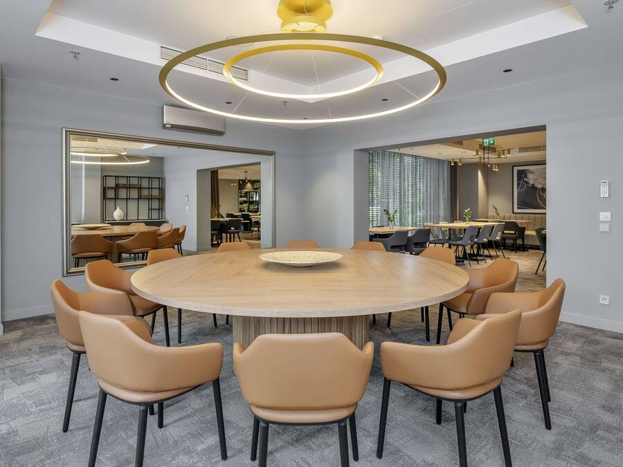 A conference room with a round table, beige chairs, and a modern ceiling design.