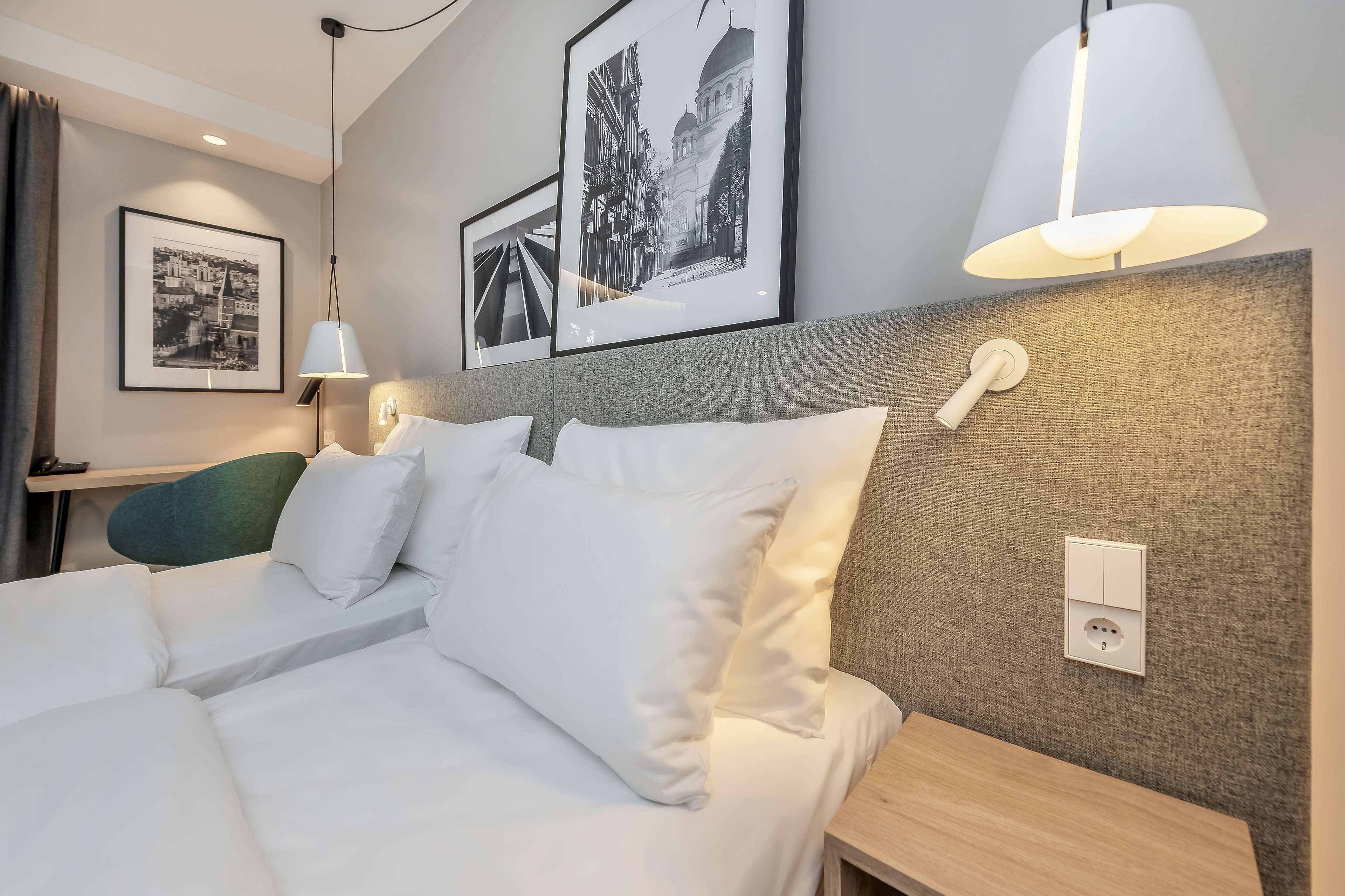 A hotel room with a bed, a bedside table, a lamp, and a wall-mounted phone.