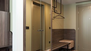 A modern bathroom with a large mirror, a bench, and a patterned floor. - Hotel Kaunas (Kaunas)