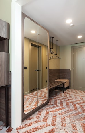 A modern bathroom with a large mirror, a bench, and a patterned floor.