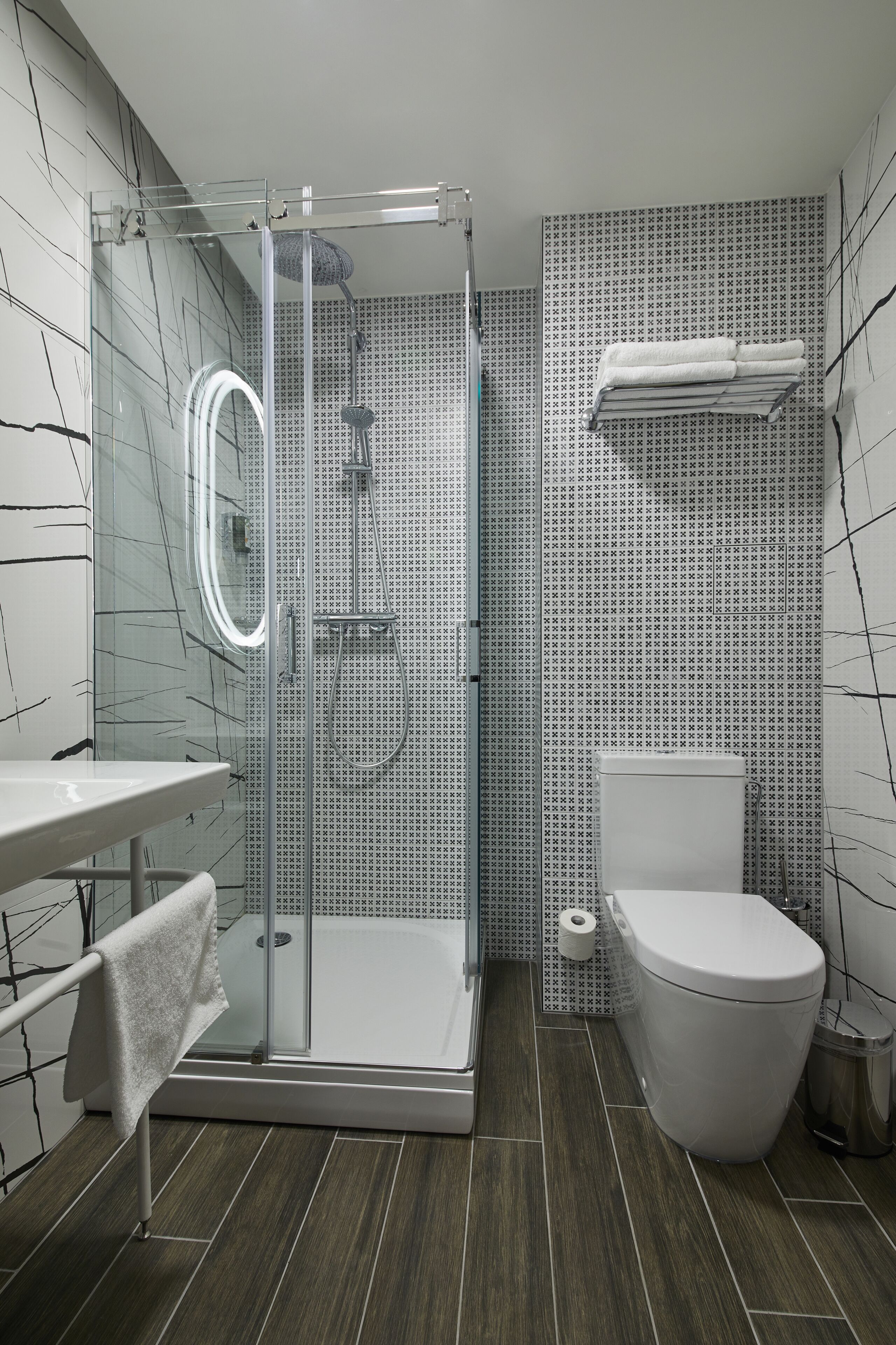 Une salle de bain moderne avec une douche à parois de verre, des toilettes blanches et un lavabo avec une serviette.