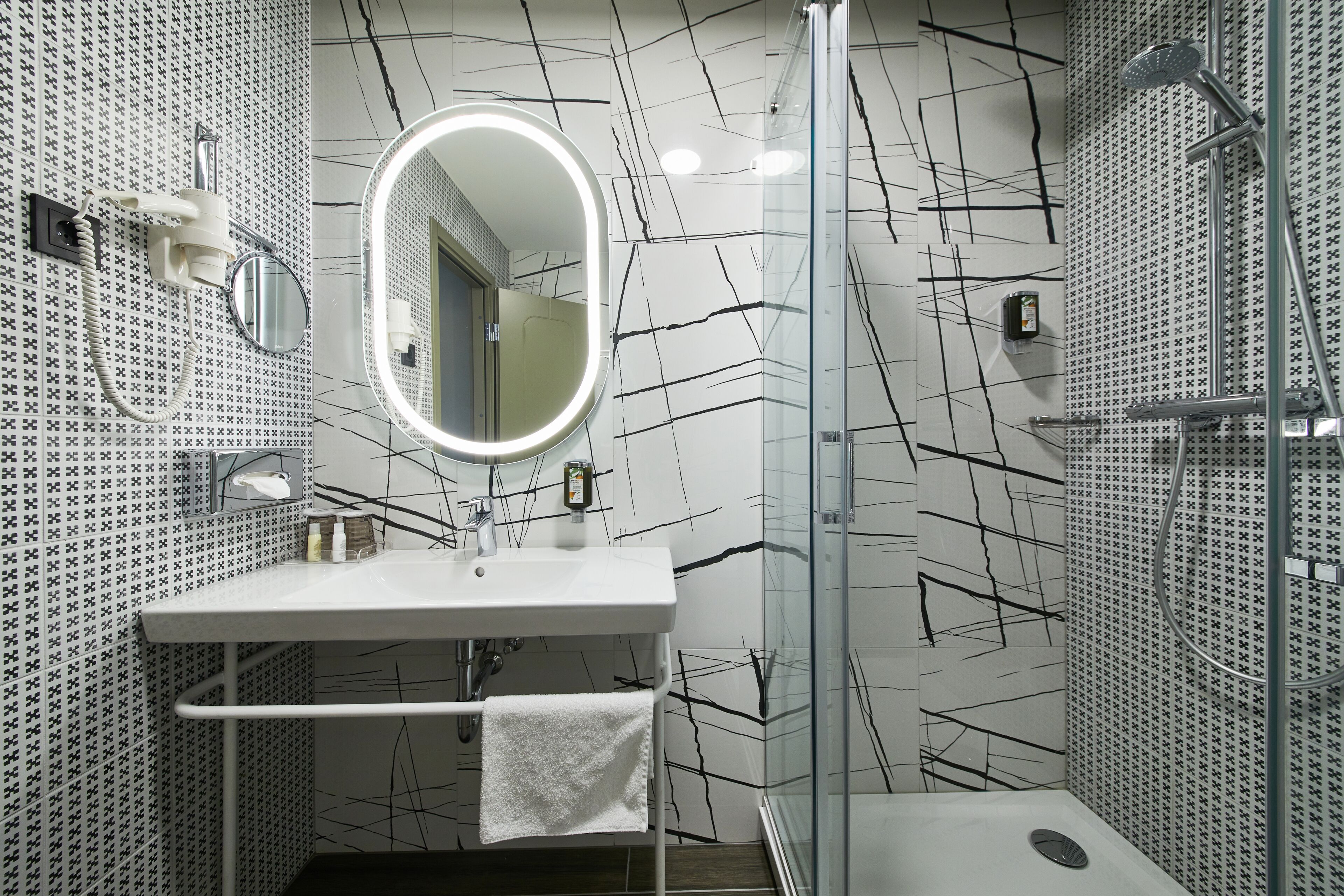 A modern bathroom with a white sink, mirror, and shower.