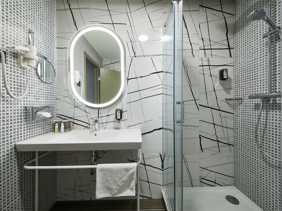 A modern bathroom with a white sink, mirror, and shower.
