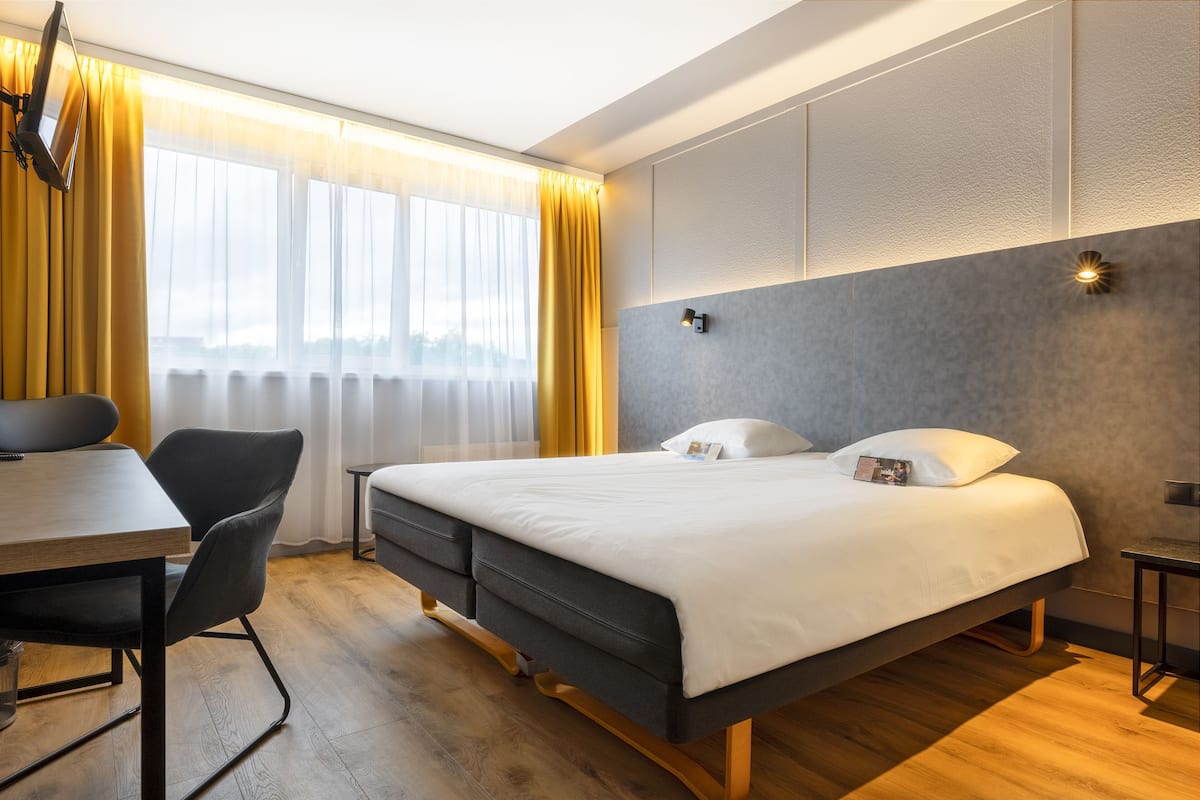 Ein modernes Hotelzimmer mit einem großen Bett, einem Schreibtisch und einem Stuhl.