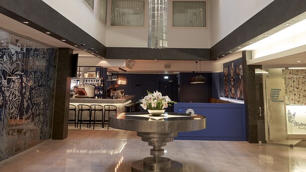 A spacious lobby with a central chandelier, a reception desk, and a bar area. - Hotel Metropol (Tallinn)