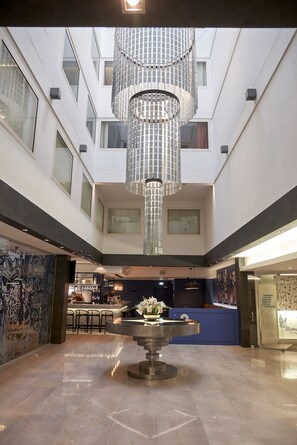A spacious lobby with a central chandelier, a reception desk, and a bar area. - Hotel Metropol (Tallinn)