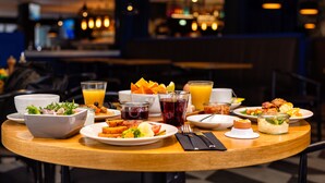 A breakfast table with various dishes, drinks, and a bowl of salad. - Hotel Metropol (Tallinn)