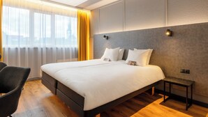A modern hotel room with a large bed, a bedside table, and a chair. - Hotel Metropol (Tallinn)