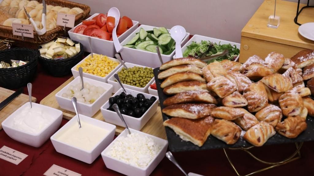 A buffet with various food items including bread, cheese, fruits, and vegetables.