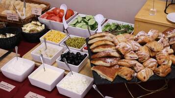 A buffet with various food items including bread, cheese, fruits, and vegetables.