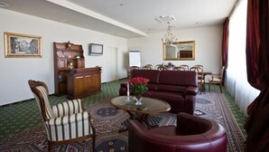 Una habitación con alfombra estampada, un armario de madera, un sofá y un comedor con sillas.
