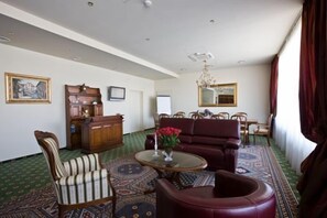 A room with a patterned carpet, a wooden cabinet, a sofa, and a dining area with chairs. - Best Baltic Hotel Kaunas (Kaunas)
