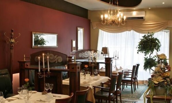A dining room with tables set for a meal, a chandelier, and a large window with curtains. - Best Baltic Hotel Kaunas (Kaunas)