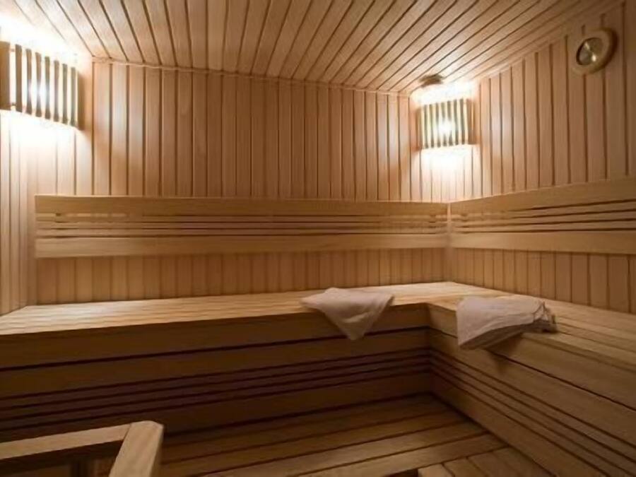 En sauna med trævægge og bænke, udstyret med vægmonterede lamper.
