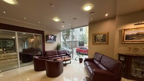 Un vestíbulo amplio con sofás de cuero, una mesa de centro y un televisor montado en la pared.