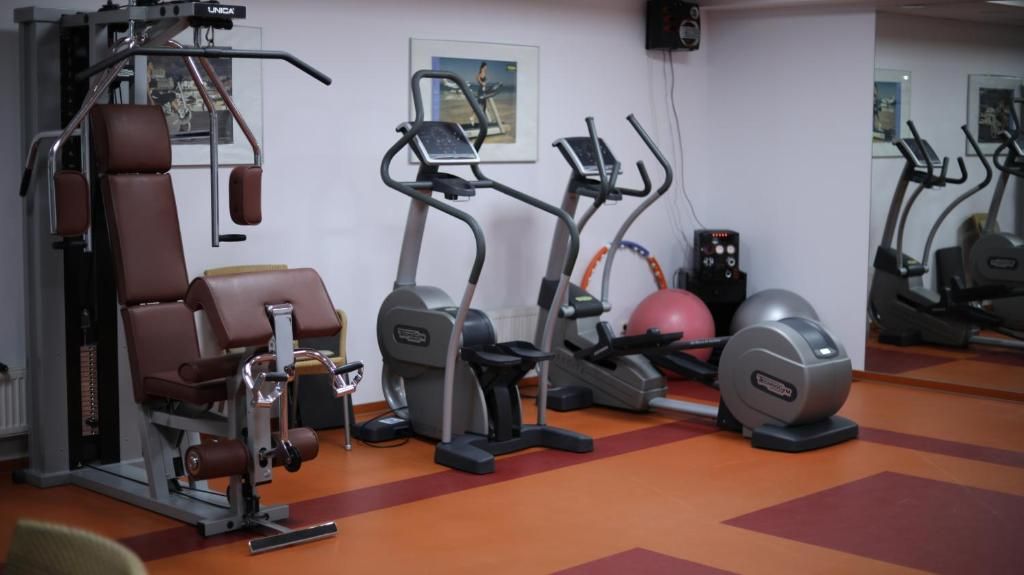 Un gimnasio con equipo de ejercicio, incluyendo una máquina de pesas, cintas de correr y una bicicleta estática.