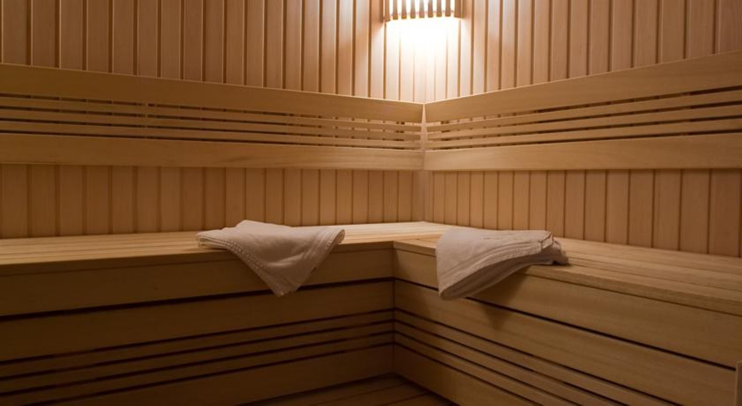 Una sauna con bancos de madera y toallas sobre ellos.