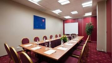 A conference room with a long table, chairs, a whiteboard, and a projector screen.
