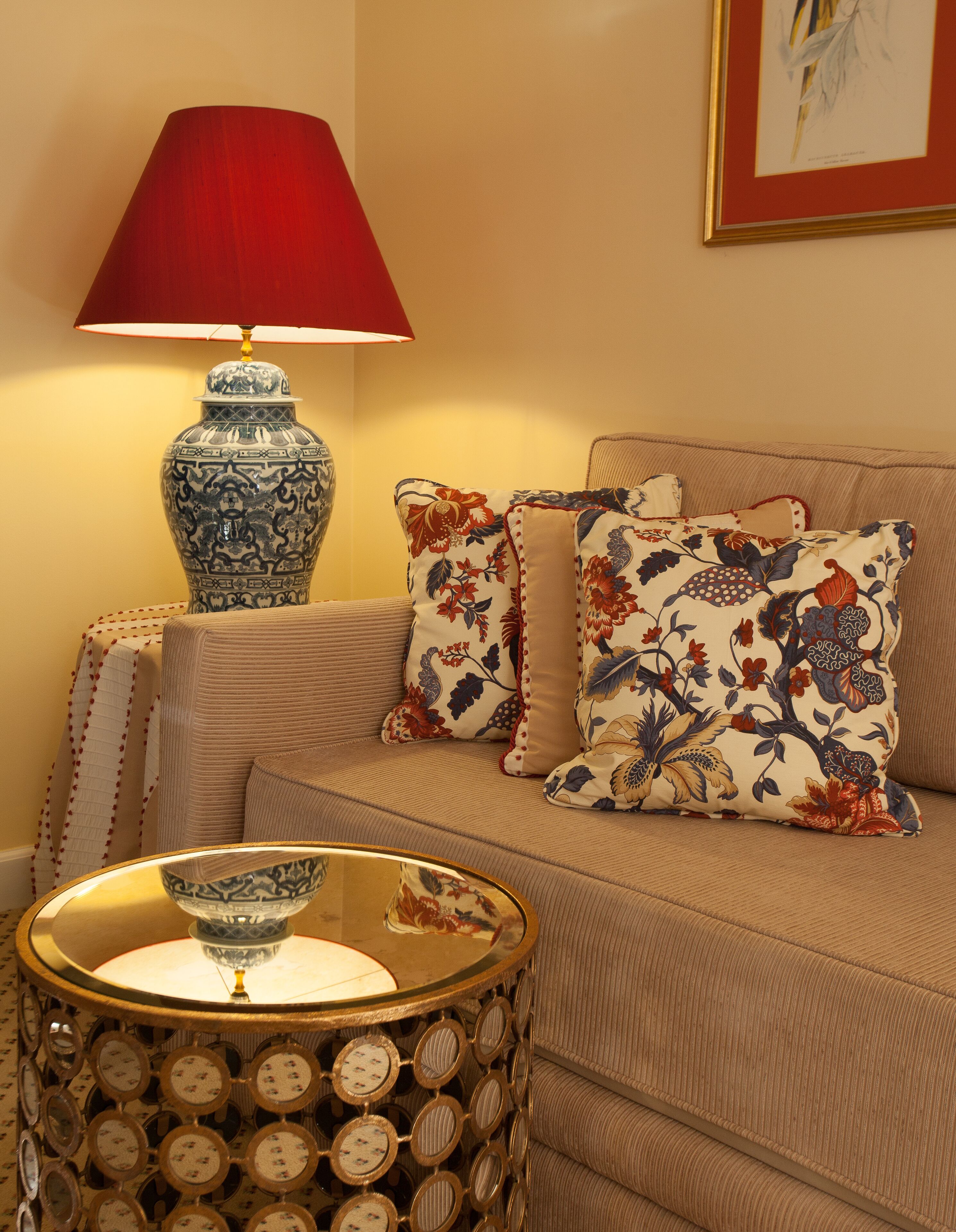 A cozy living room with a sofa, patterned cushions, a decorative lamp, and a side table with a bowl.