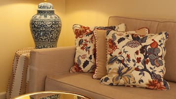 A cozy living room with a sofa, patterned cushions, a decorative lamp, and a side table with a bowl.