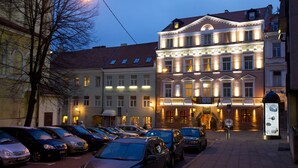Un hôtel au style architectural européen classique, caractérisé par une entrée imposante avec des fenêtres illuminées et une façade bien éclairée.