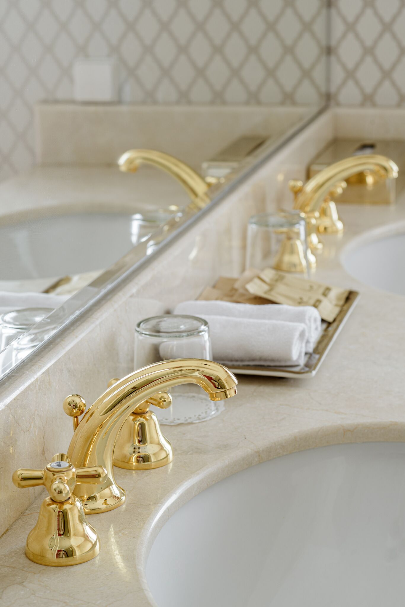 A bathroom with two sinks, gold faucets, and a mirror reflecting the setup.