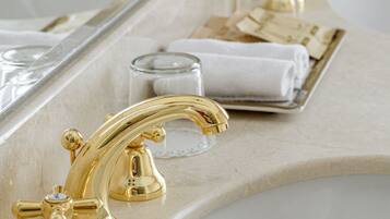 A bathroom with two sinks, gold faucets, and a mirror reflecting the setup.