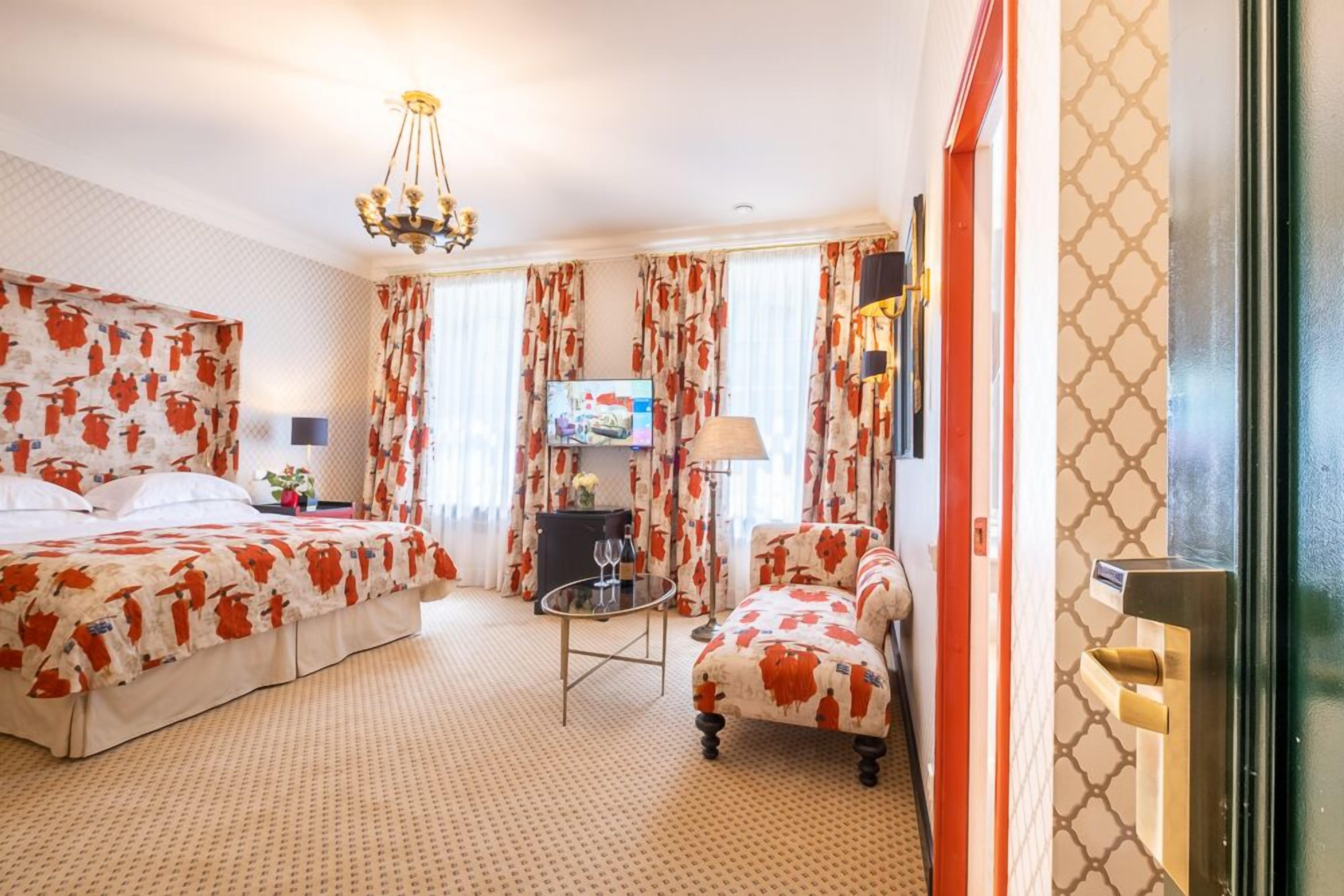 Une chambre d’hôtel avec un grand lit, un lit plus petit, un canapé, une télévision et une lampe.