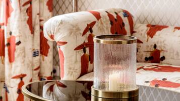 A room with a round glass table, a lamp, and a sofa with patterned upholstery.