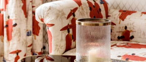 A room with a round glass table, a lamp, and a sofa with patterned upholstery.